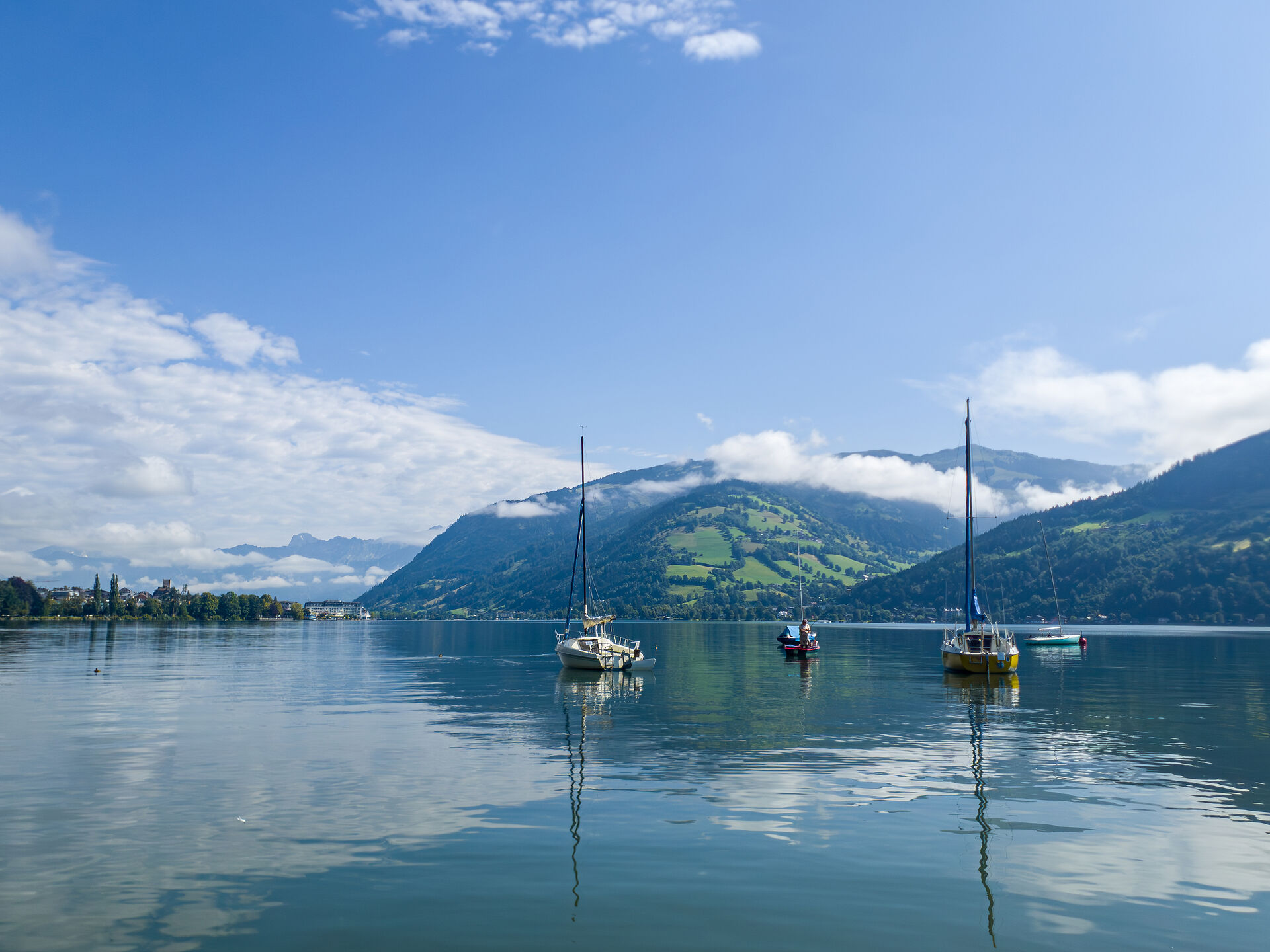 Vier Segelboote im Zeller See. Im Hintergrund sieht man die Berge.